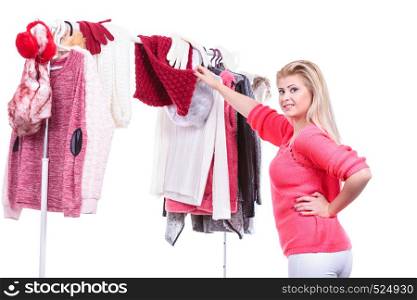 Young woman indecision in wardrobe home closet, teen blonde girl choosing her warm fashion outfit on clothing rack. Picking winter autumn clothes, shopping concept.. Woman in home closet choosing clothing, indecision