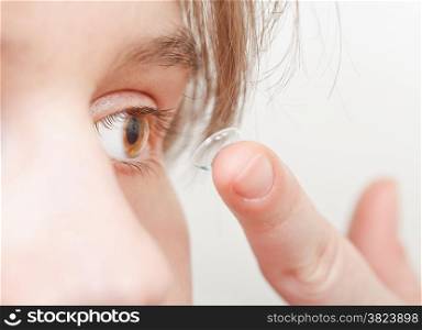 young woman inserts corrective lens in eye close up