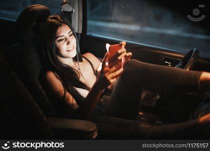 Young woman inside a car using her smartphone