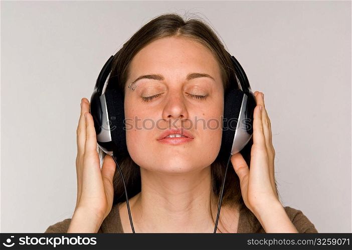 Young woman intently listening to music on headphones.