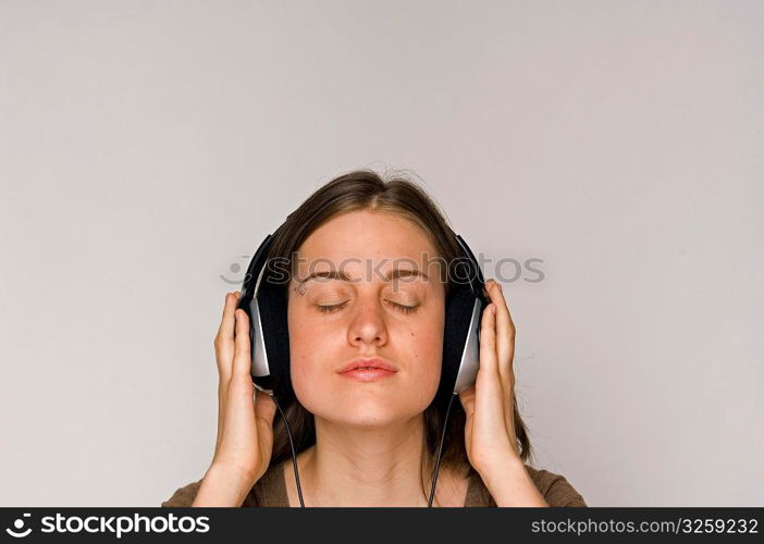 Young woman intently listening to music on headphones.