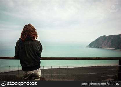 Young woman is admiring the seaside view from a hill