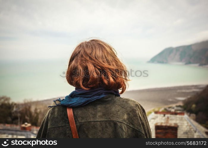 Young woman is admiring the seaside view from a hill