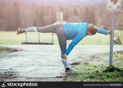 Young woman is bending and stretching before going to run