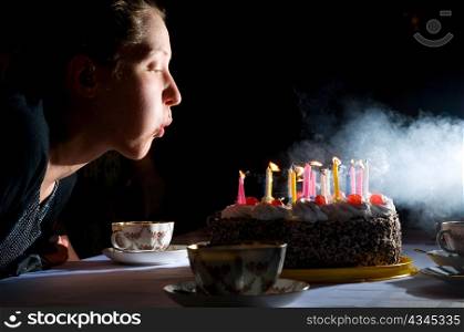 young woman is blowing out candles on cake