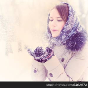 young woman is blowing snow in winter park. blowing snow