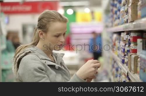 Young woman is choosing food for her child in the supermarket.