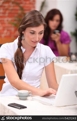 young woman is doing computer in a cafe