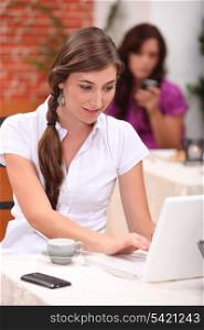young woman is doing computer in a cafe