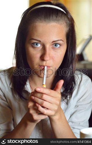 young woman is lighting a cigarette in a cafe