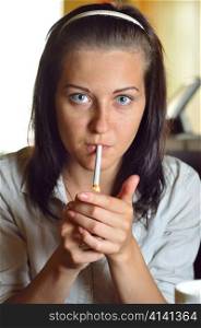 young woman is lighting a cigarette in a cafe
