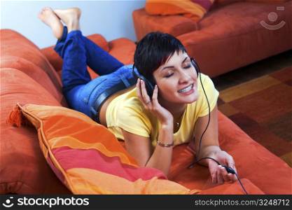 Young woman is listening music on a headphone in the livingroom.