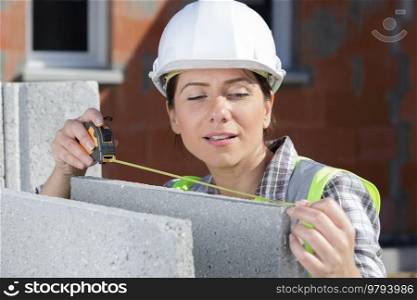 young woman is measuring a wall with measuring tape