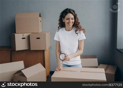 Young woman is packing boxes with duct tape. Lady is wrapping cardboard containers with tape. Moving service worker preparing boxes for shipping. Courier is packing things for and storage.. Young woman is packing cardboard containers with tape. Moving service worker preparing boxes.