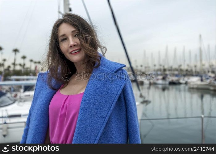 Young woman is posing on a boat at the yacht marina