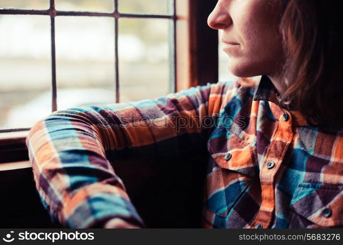 Young woman is sitting and looking out the window