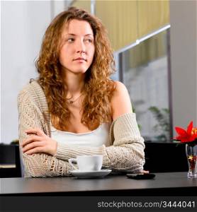 young woman is sitting at cafe and looking sideways