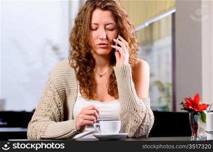 young woman is sitting at cafe and talking phone
