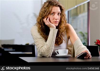 young woman is sitting at cafe and waiting for someone