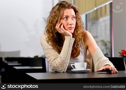 young woman is sitting at cafe and waiting for someone