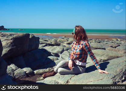 Young woman is sitting on a rocky beach