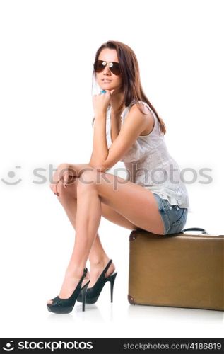 young woman is sitting on old leather case, isolated on white