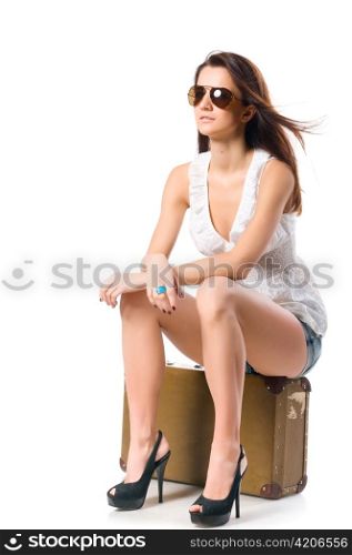 young woman is sitting on old leather case, isolated on white