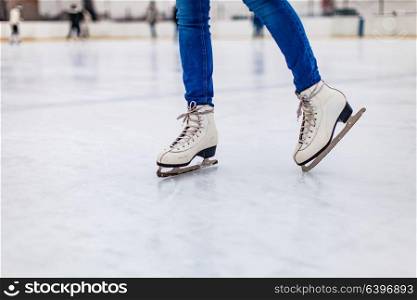 Young woman is skating on the rink, close up legs. Skates on the rink