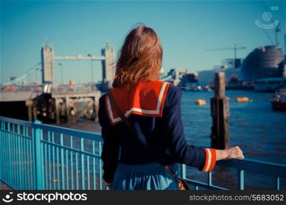 Young woman is standing on the bank of the river Thames in London on a sunny day
