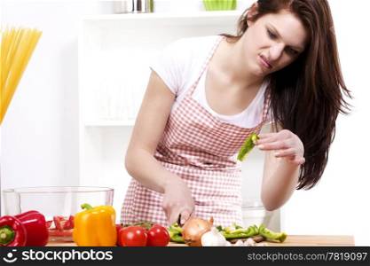 young woman is suspicious about the vegetable. young woman is suspicious about the paprika she was chopping