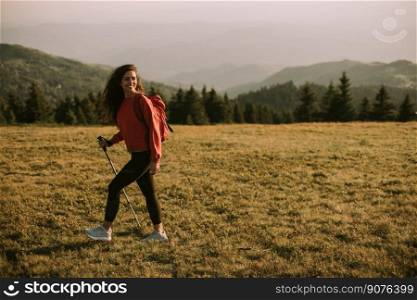Young woman is taking a scenic hike on a hill, carrying all her necessary gear in a backpack. She appears to be a seasoned hiker, enjoying the challenge and beauty of the outdoor experience