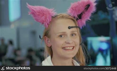 Young woman is trying on Brainwave Controlled Cat Ears and taking selfie. Ears are moving depending on her mood.