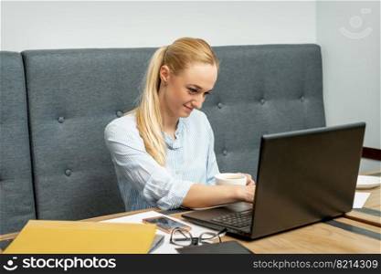 Young woman is using laptop during online learning at home office.. Woman is working on laptop at home office.
