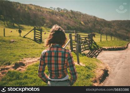 Young woman is walking around a ranch with cattle in the distance