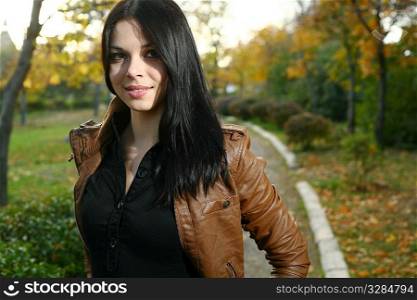 Young woman is walking outdoors in autumn alley