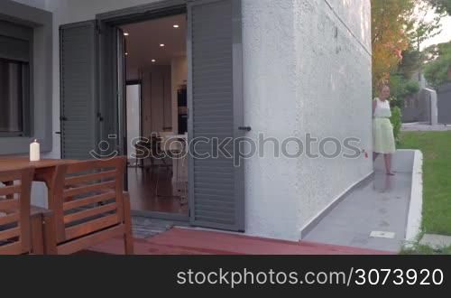 Young woman is washing her feet from the outdoor tap, wiping them at a door-mat and coming into rented apartment.