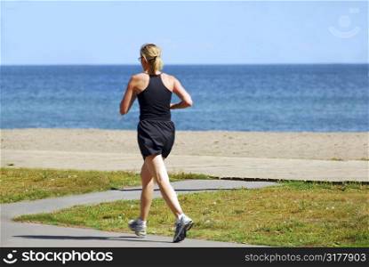 Young woman joggin by sea side in the summer