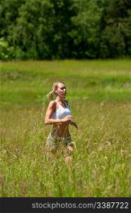 Young woman jogging in a meadow on a sunny day