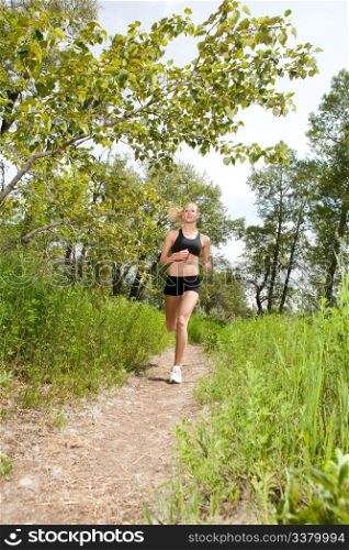 Young woman jogging outdoors in summer on trail