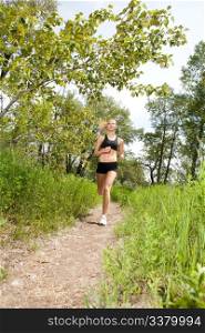 Young woman jogging outdoors in summer on trail