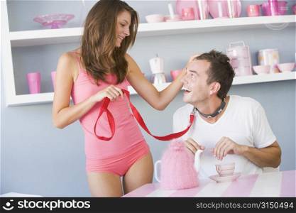 Young woman joking around with boyfriend on a leash