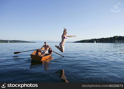 Young woman jumping off a row boat