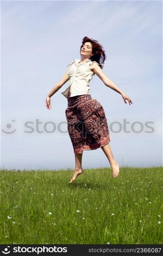 Young woman jumping on a beautiful green meadow