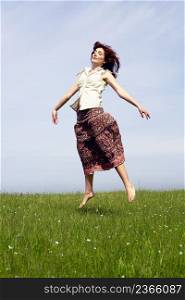 Young woman jumping on a beautiful green meadow