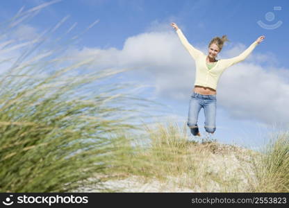 Young woman jumping on a sand hill