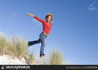 Young woman jumping on a sand hill