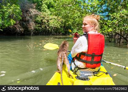 Young woman kayaking on canoe with wild monkey