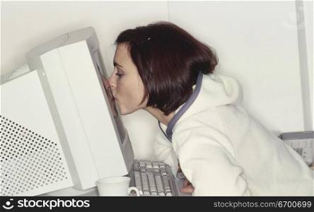 Young woman kissing a computer monitor