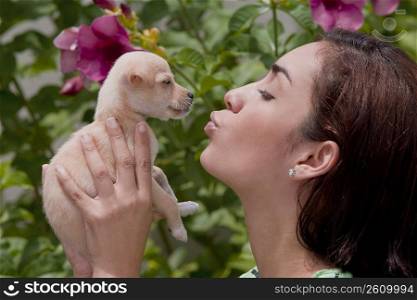 Young woman kissing a puppy