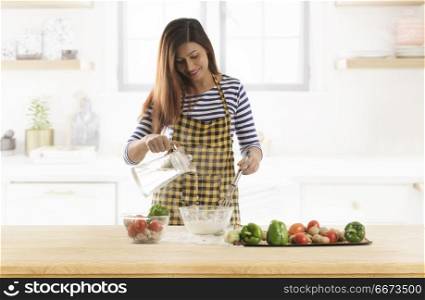 Young woman kneading dough in kitchen
